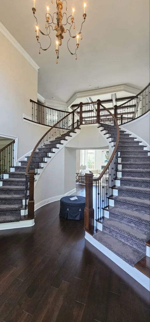 Curved staircase with white trim and dark wood flooring
